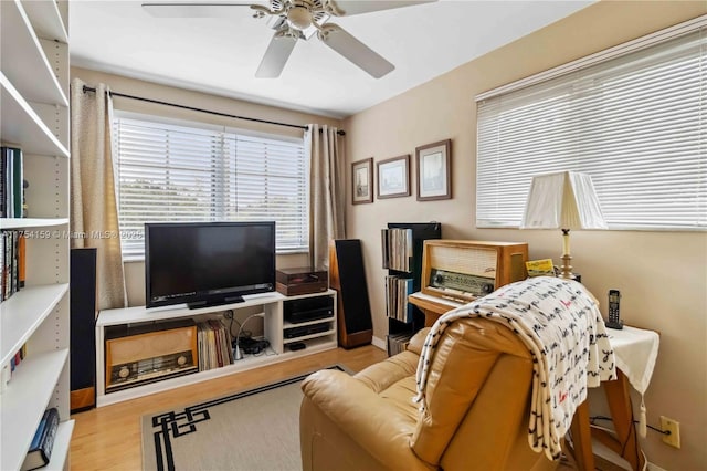 living area featuring ceiling fan, baseboards, and wood finished floors