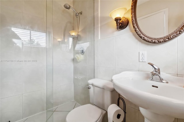 full bathroom featuring tile walls, backsplash, toilet, a tile shower, and a sink