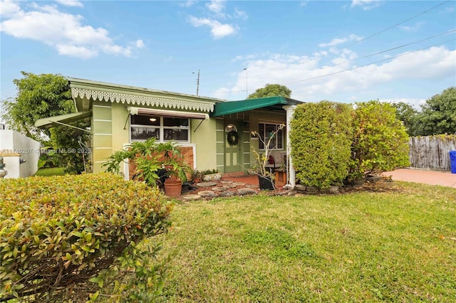 view of front of property with fence, a front lawn, and stucco siding