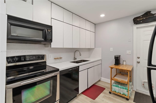 400 S 62nd Ter, Hollywood, FL 33023 - kitchen with a sink, white cabinets, light countertops, light wood-type flooring, and black appliances