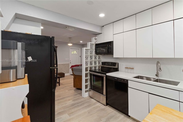 400 S 62nd Ter, Hollywood, FL 33023 - kitchen with black appliances, light wood-style flooring, white cabinetry, and a sink