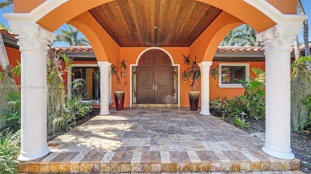 view of exterior entry with stucco siding and a tiled roof