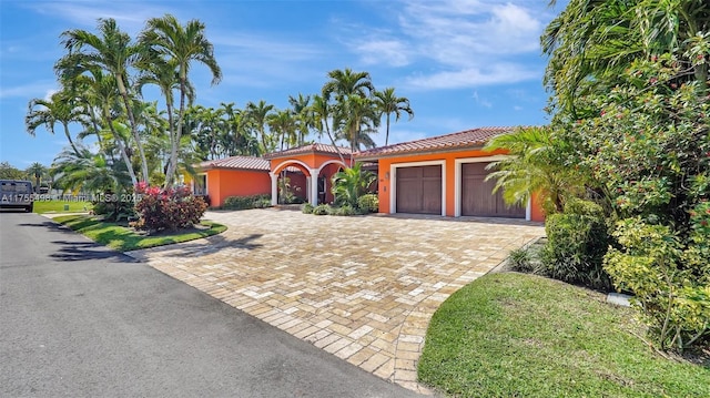 mediterranean / spanish-style home with decorative driveway, a garage, stucco siding, and a tile roof