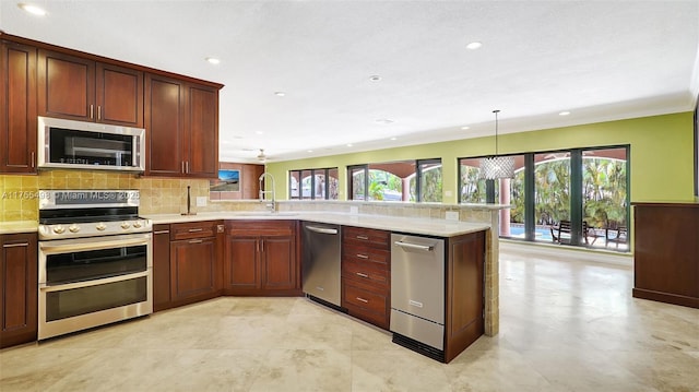 kitchen featuring a peninsula, a sink, light countertops, appliances with stainless steel finishes, and backsplash