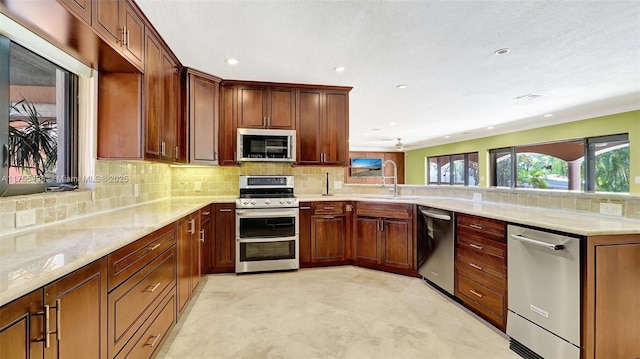 kitchen featuring a sink, tasteful backsplash, appliances with stainless steel finishes, and a peninsula