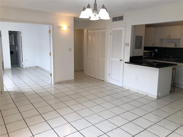 kitchen with a notable chandelier, light tile patterned floors, dark countertops, visible vents, and a sink