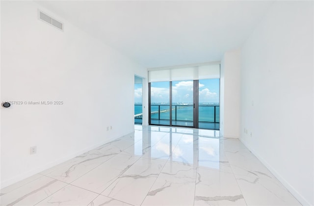 empty room with baseboards, marble finish floor, visible vents, and floor to ceiling windows