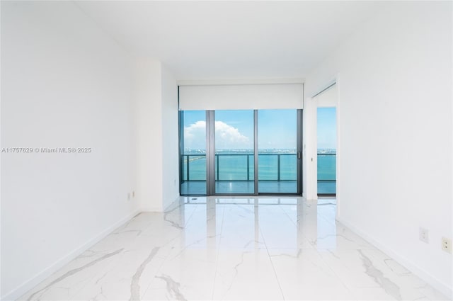 empty room featuring marble finish floor and baseboards