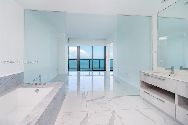 bathroom featuring marble finish floor, vanity, and a bath