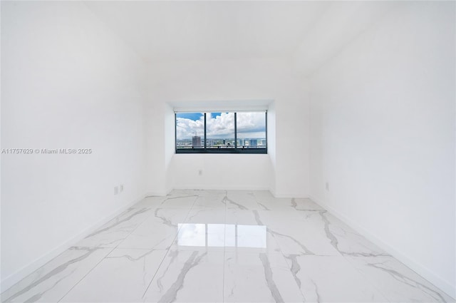 unfurnished room featuring marble finish floor and baseboards