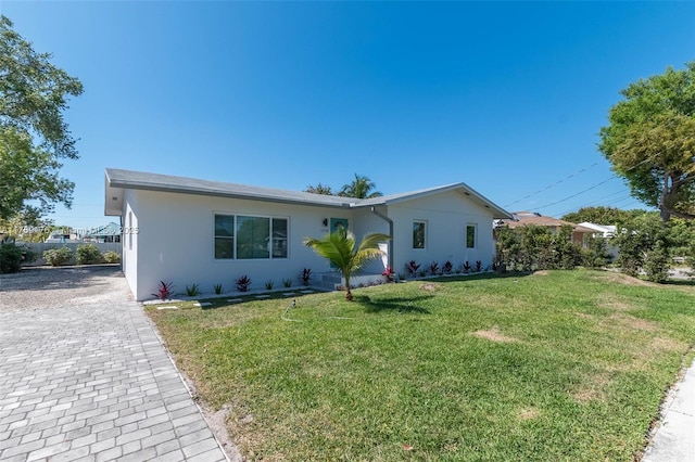 single story home featuring decorative driveway, a front yard, and stucco siding