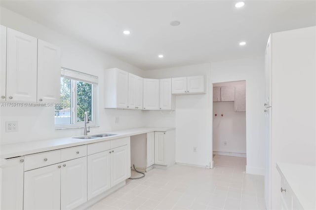 kitchen featuring light countertops, a sink, white cabinetry, and recessed lighting