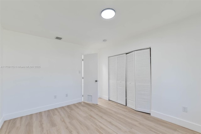 unfurnished bedroom with a closet, visible vents, light wood finished floors, and baseboards