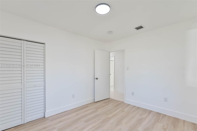 unfurnished bedroom featuring light wood finished floors, a closet, visible vents, and baseboards