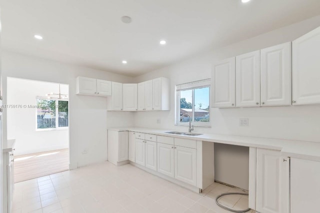 kitchen with light countertops, a sink, white cabinetry, and recessed lighting