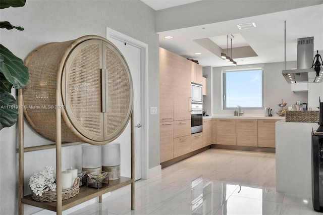 kitchen featuring modern cabinets, extractor fan, light countertops, light brown cabinets, and stainless steel oven