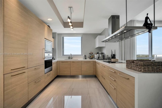 kitchen featuring stainless steel appliances, a peninsula, a sink, light brown cabinetry, and modern cabinets