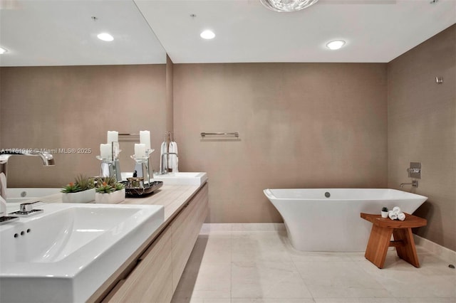 full bathroom with a freestanding bath, double vanity, a sink, and baseboards