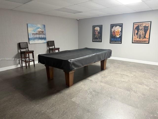 rec room with concrete floors, billiards, a paneled ceiling, and baseboards