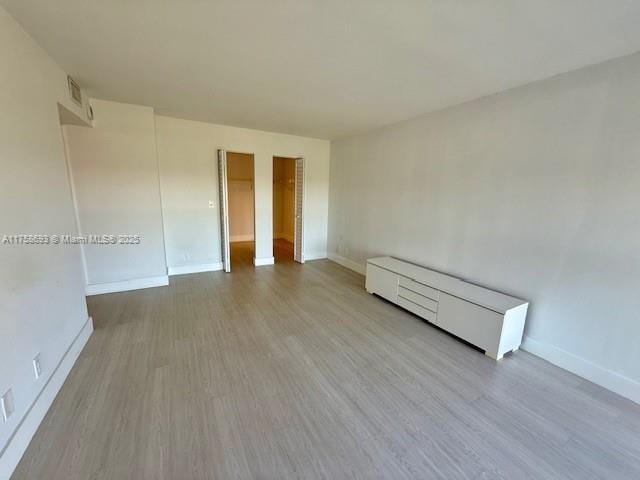 empty room featuring visible vents, baseboards, and wood finished floors