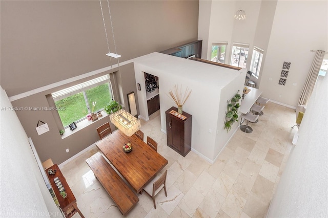 living area featuring marble finish floor, a towering ceiling, and baseboards