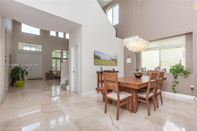 dining room with baseboards, marble finish floor, stairs, a high ceiling, and a notable chandelier