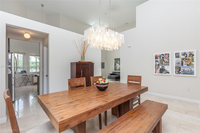 dining space with baseboards and a notable chandelier