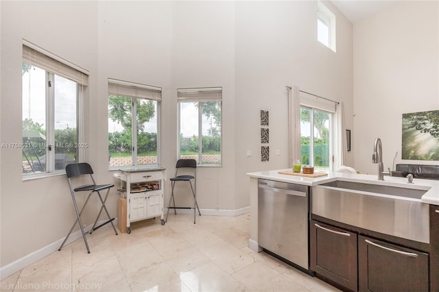 kitchen with a sink, a wealth of natural light, baseboards, and dishwasher