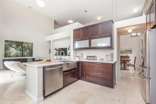 kitchen featuring light countertops, appliances with stainless steel finishes, a peninsula, and dark brown cabinets