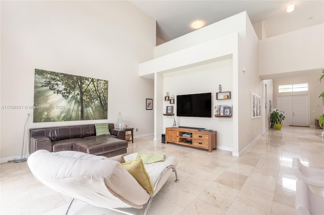 living area featuring marble finish floor, baseboards, and a high ceiling