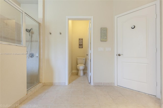 full bathroom featuring a stall shower, baseboards, tile patterned flooring, and toilet