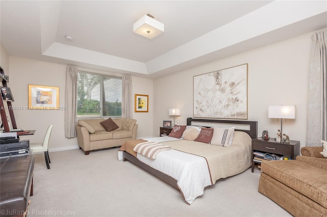 bedroom featuring baseboards, a tray ceiling, and light colored carpet