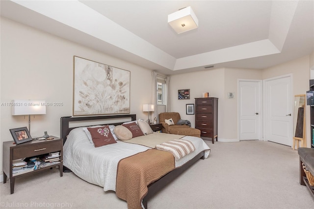 bedroom featuring a tray ceiling, light colored carpet, and visible vents