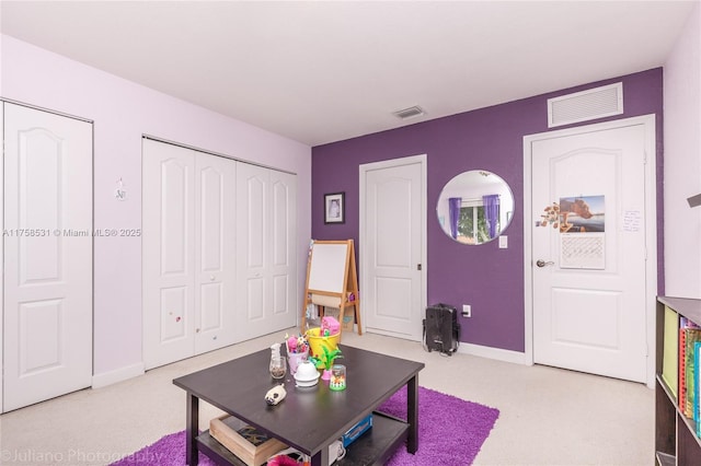 living area with baseboards, visible vents, and light colored carpet