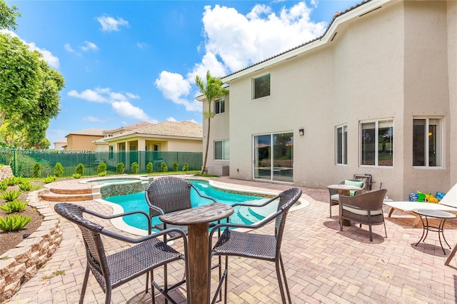 view of pool with a patio area, a pool with connected hot tub, and fence