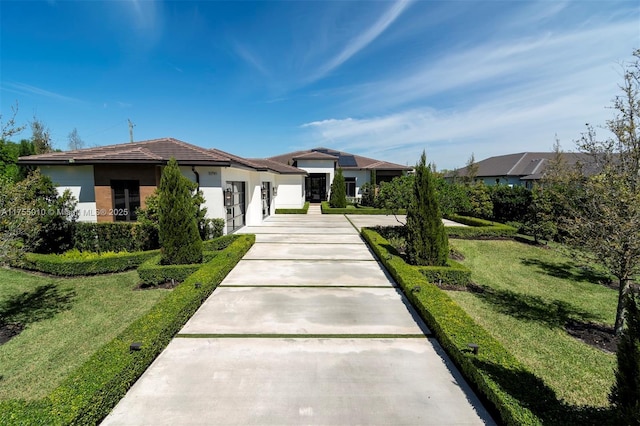 view of front of property featuring a front yard, an attached garage, driveway, and stucco siding