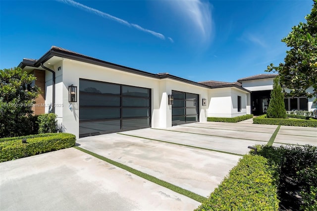 view of front of house featuring stucco siding, concrete driveway, and an attached garage