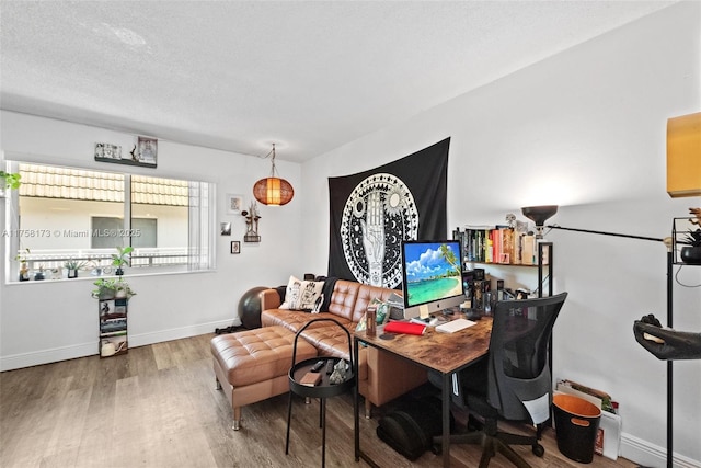 office space featuring a textured ceiling, baseboards, and wood finished floors