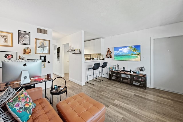 living room featuring light wood-type flooring, baseboards, and visible vents