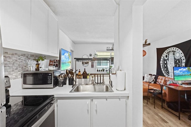 kitchen with white cabinets, stainless steel appliances, light countertops, light wood-type flooring, and backsplash