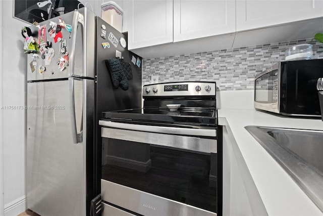 kitchen featuring white cabinets, decorative backsplash, appliances with stainless steel finishes, light countertops, and a sink