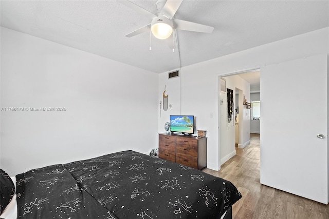 bedroom featuring ceiling fan, visible vents, and wood finished floors