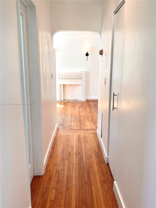 corridor featuring wood-type flooring, visible vents, and baseboards