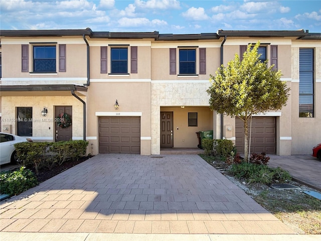 townhome / multi-family property featuring decorative driveway, an attached garage, and stucco siding