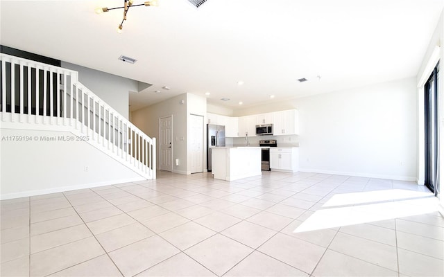 unfurnished living room featuring recessed lighting, light tile patterned flooring, baseboards, and stairs