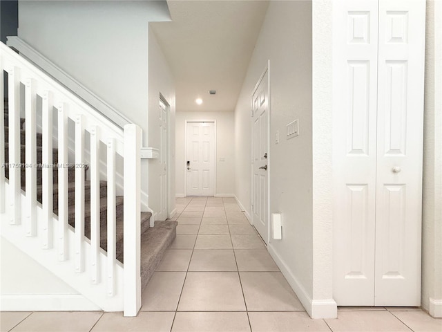 hallway featuring light tile patterned floors, stairs, and baseboards