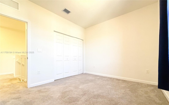 unfurnished bedroom featuring baseboards, a closet, visible vents, and light colored carpet