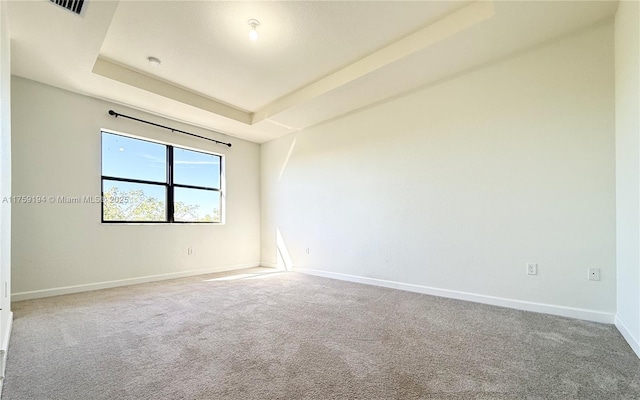 carpeted spare room with baseboards and a tray ceiling