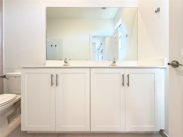 full bathroom with toilet, double vanity, and a sink