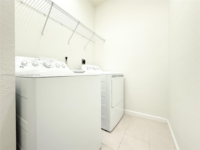 laundry room featuring light tile patterned floors, laundry area, washing machine and dryer, and baseboards